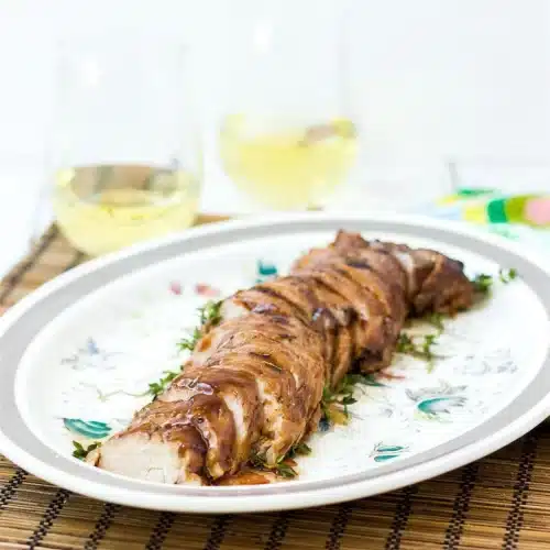 Whole glazed pork tenderloin resting on a floral platter