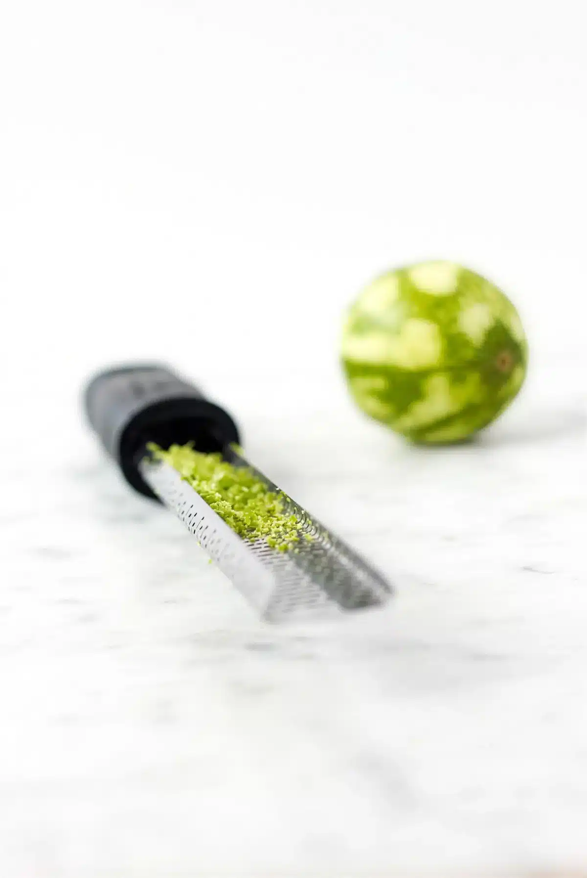 Zest being grated from a lime with a fine grater