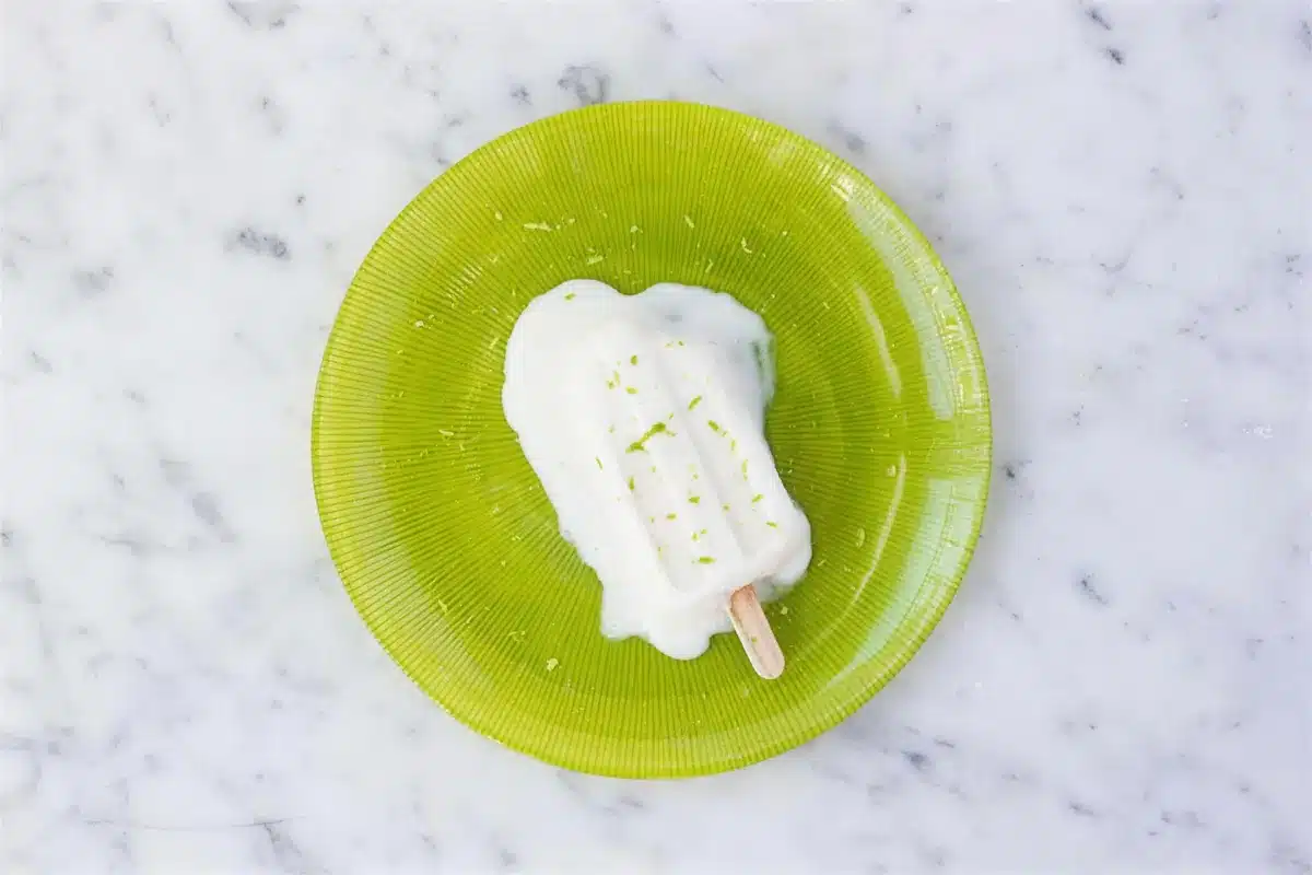 Coconut popsicles beginning to melt on a green glass plate