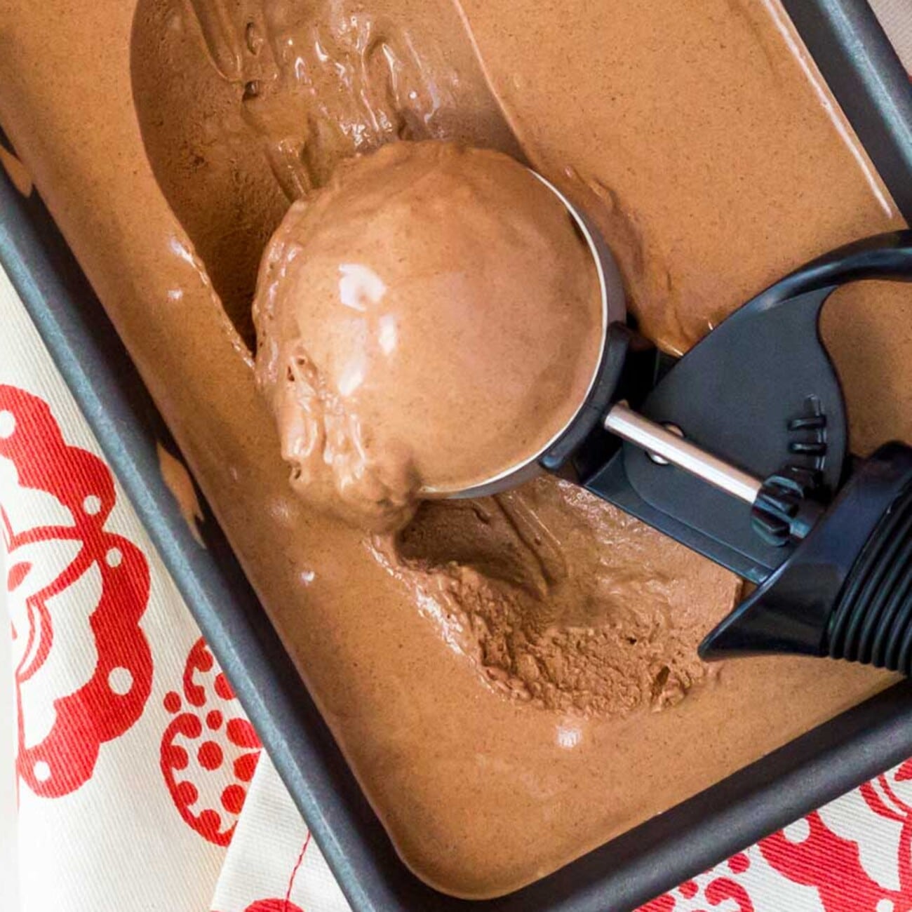 A scoop of chocolate caramel ice cream lifted from the tub