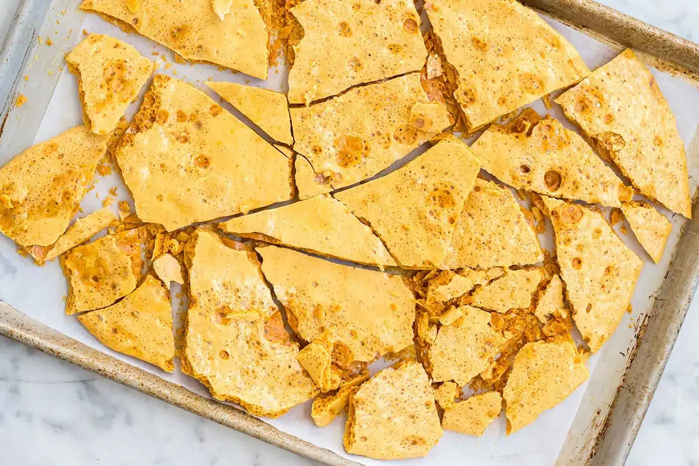 Golden shards of aerated candy broken up across a sheet pan