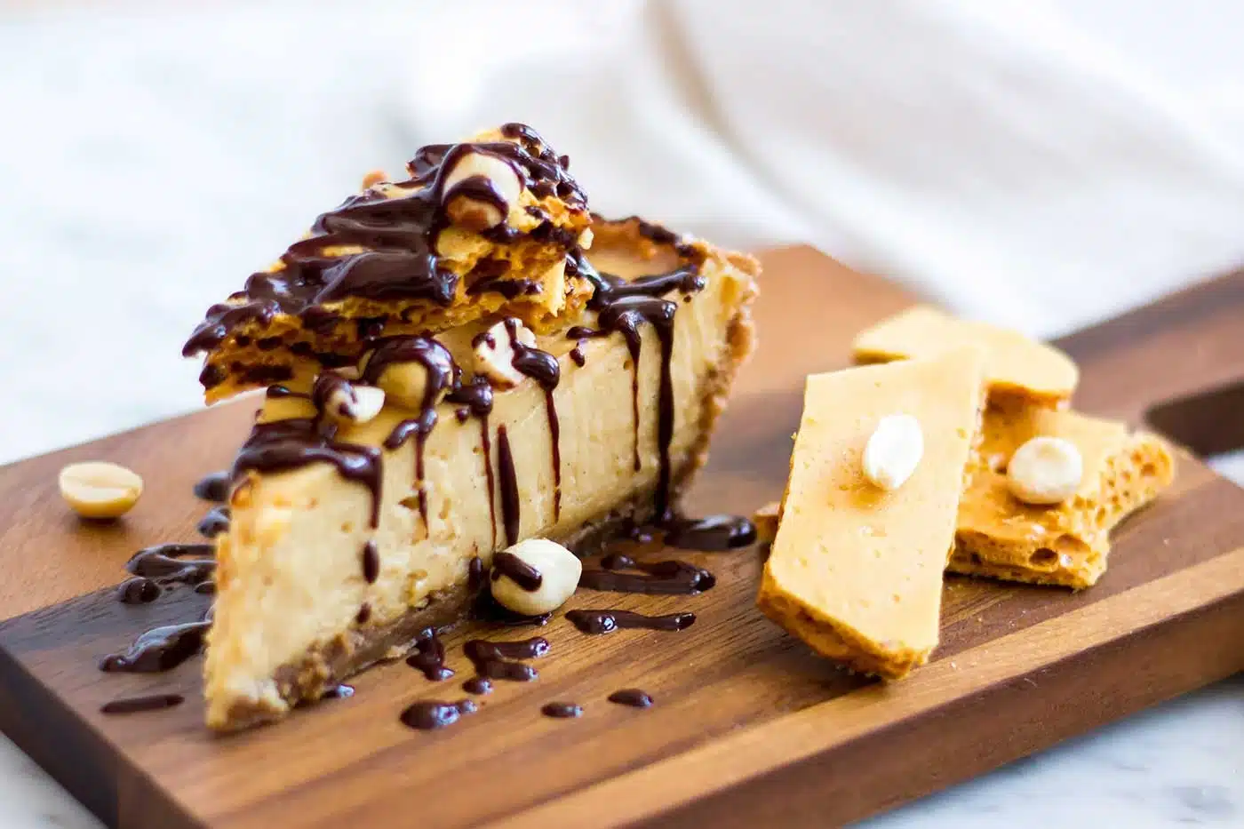 A slice of peanut butter cream pie on a wooden board beside pieces of honeycomb