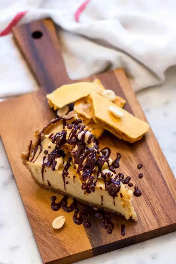 Wedge of chilled pie on a wooden board with candy pieces and a linen cloth behind