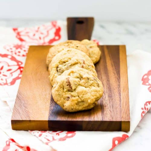 Toffee cookies fanned across a walnut board with a red print napkin