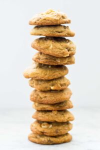A tall stack of a dozen cookies against a plain wall