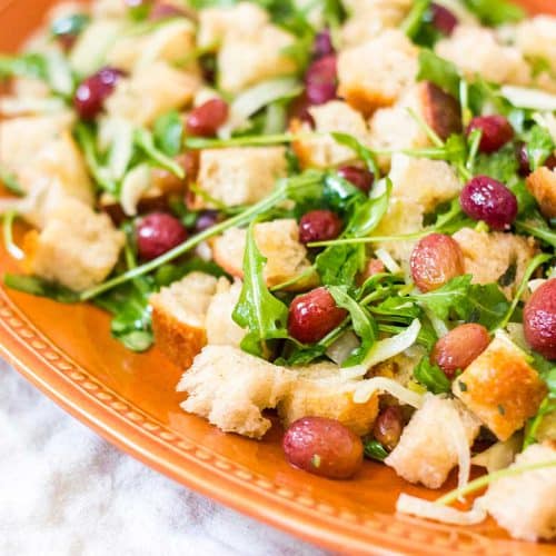 Winter panzanella salad tossed and served on a wide terracotta plate