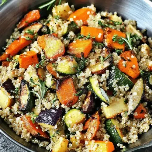 Metal bowl of grains and charred vegetable chunks with rosemary
