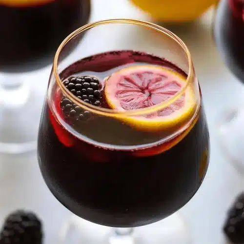 A close view of a lemon wheel floating in dark red wine punch