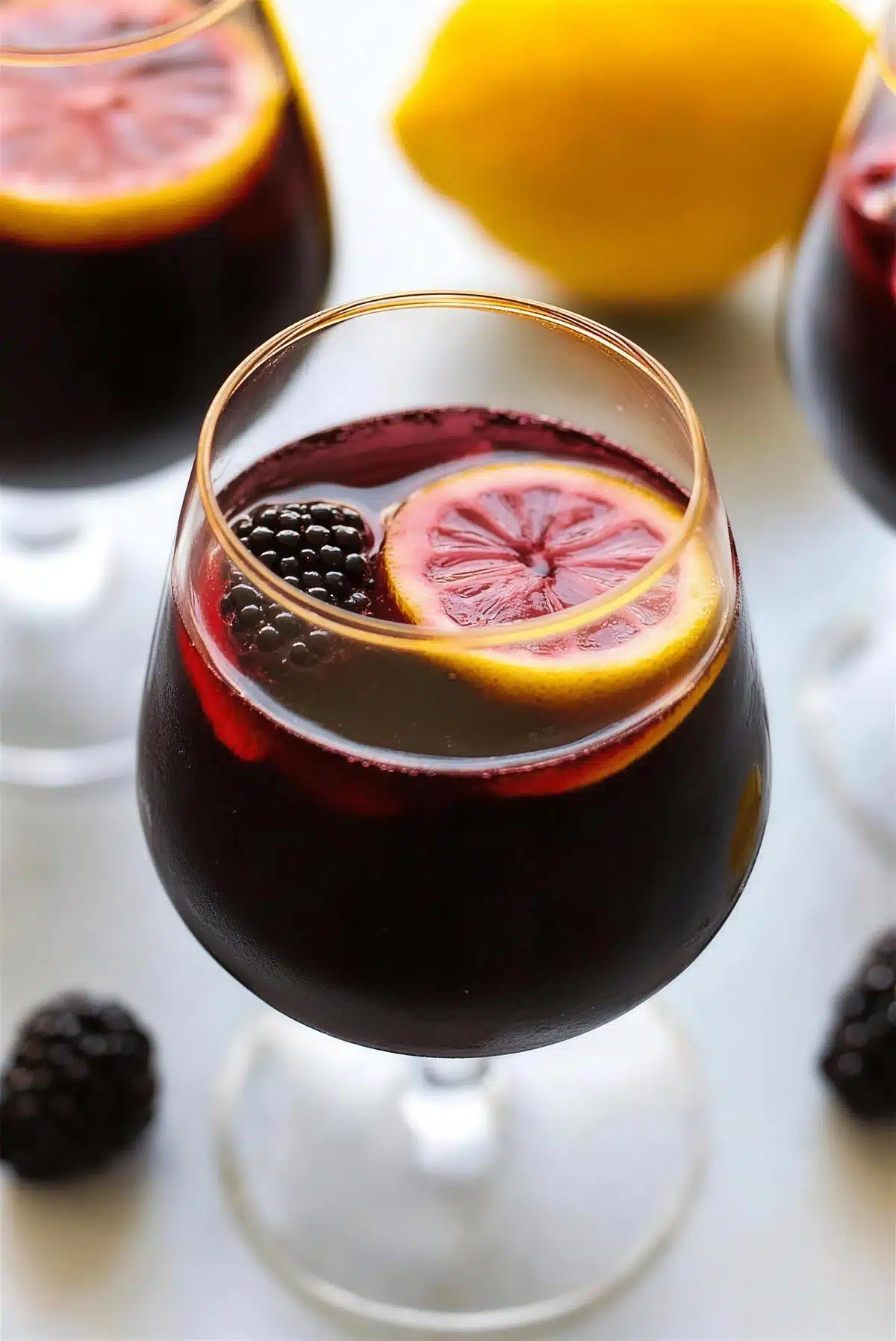 A close view of a lemon wheel floating in dark red wine punch