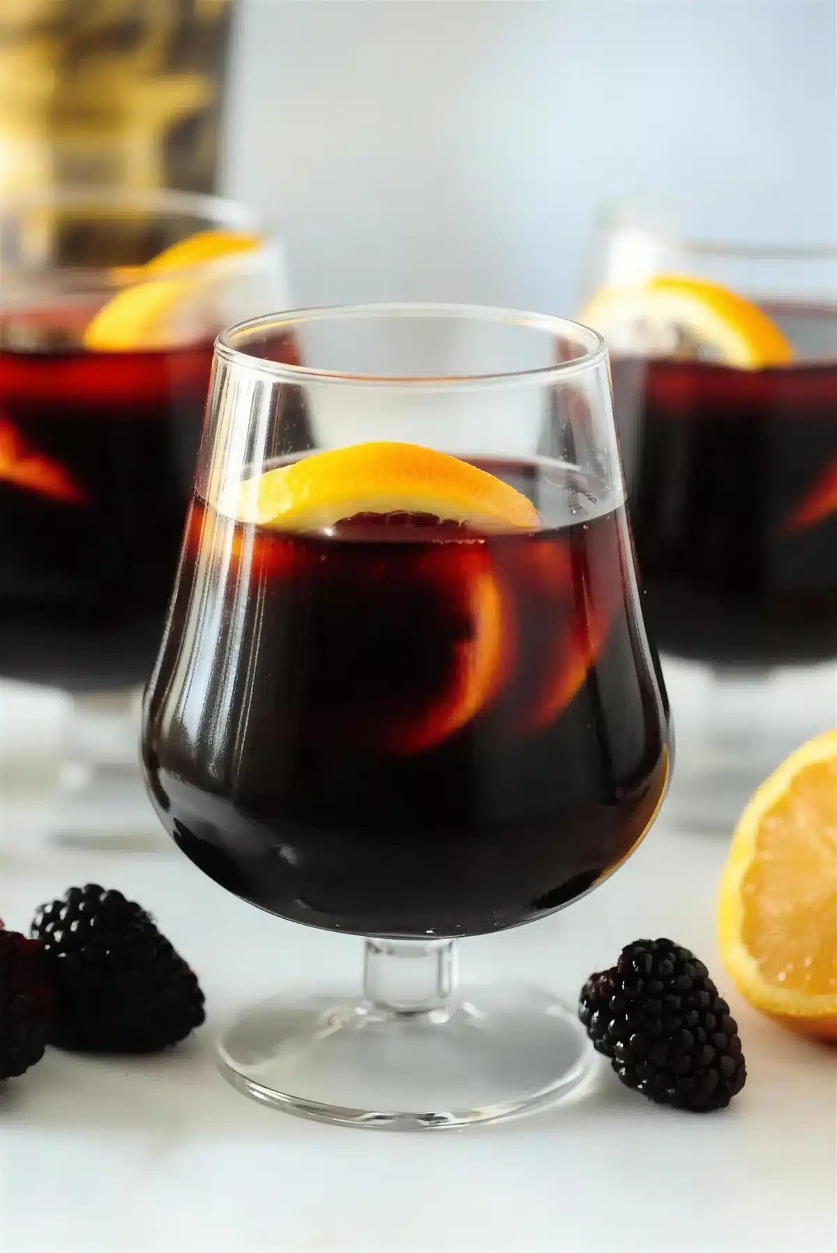 Blackberry sangria in a stemmed glass with an orange crescent