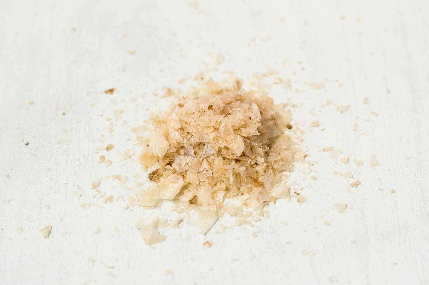 Coarse salt crystals heaped on a pale wooden board