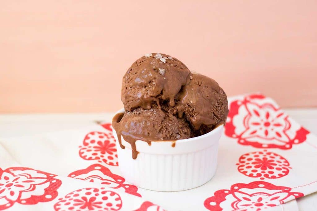 Scoops of chocolate ice cream in a small ramekin on a patterned napkin