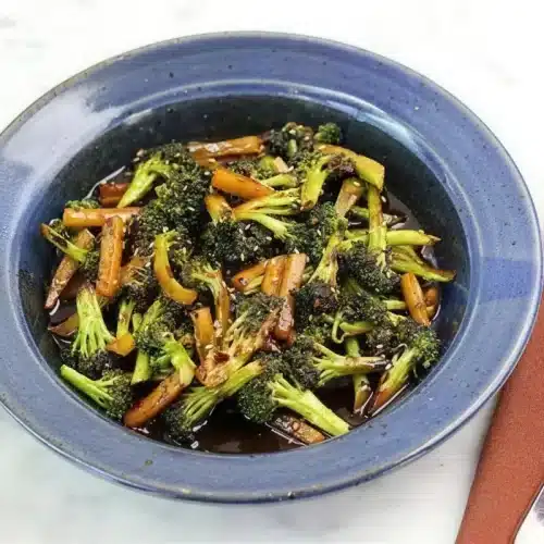 Asian broccoli in a blue bowl with a glossy dark glaze and sesame seeds