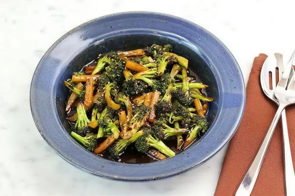 Asian broccoli in a blue bowl with a glossy dark glaze and sesame seeds