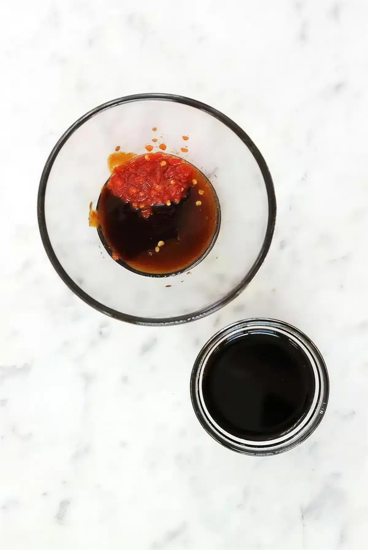 Dark glaze and chile paste in a glass bowl beside a jar of soy sauce