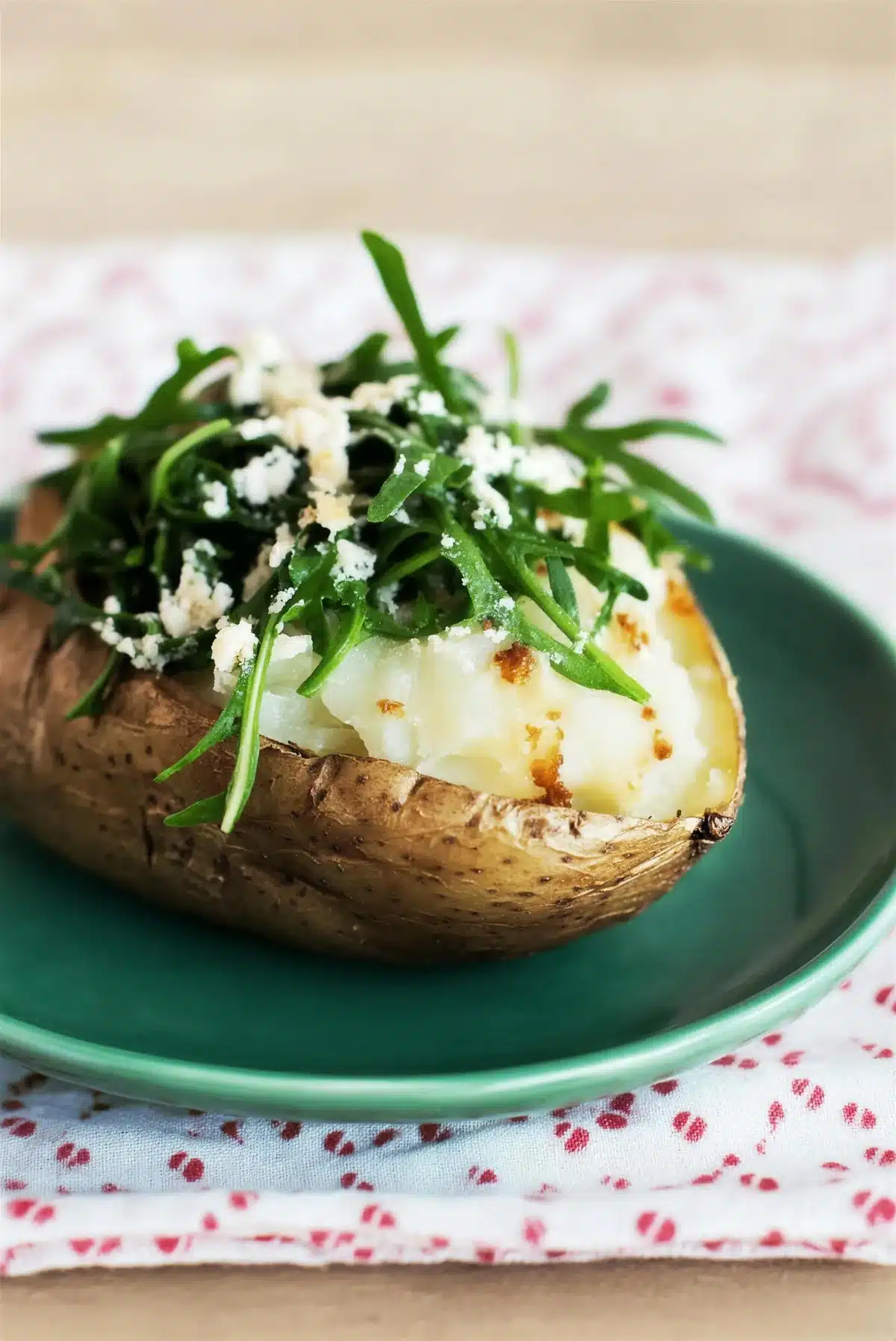 Sauteed arugula piled on a split baked potato with shredded cheese