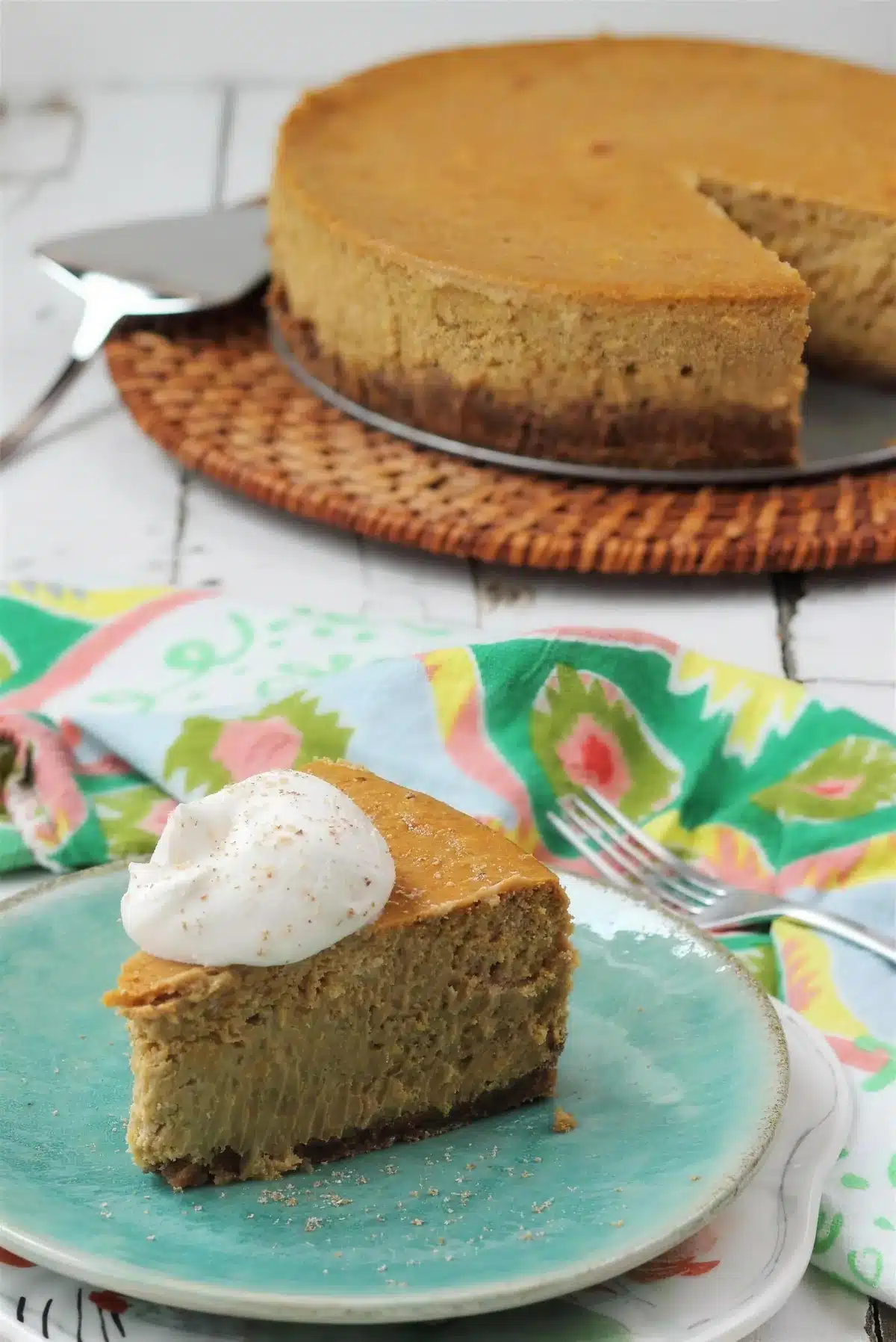 Pumpkin cheesecake slice on a turquoise plate with the cut cake behind