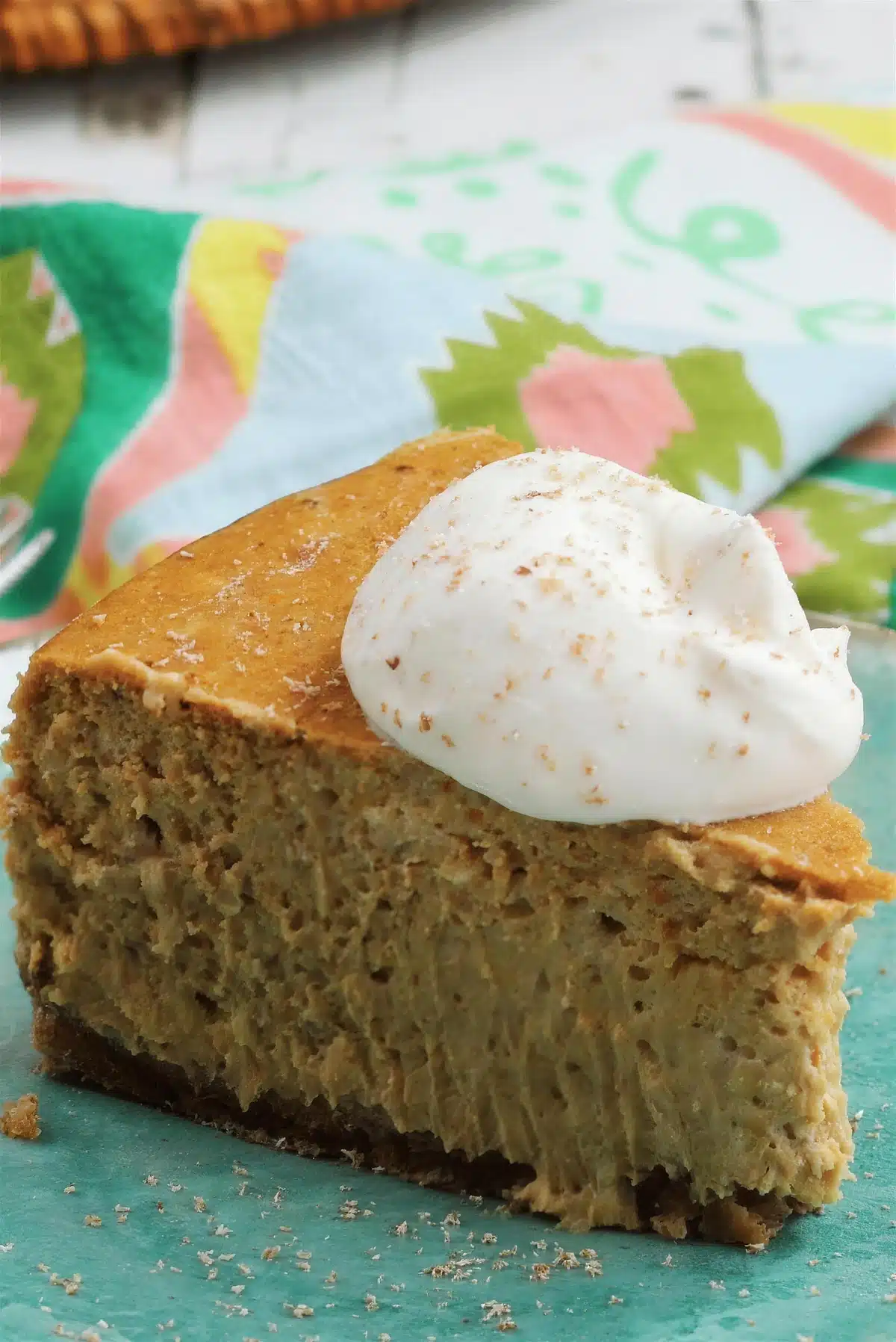 Close-up of a dense orange dessert wedge with cream and grated spice on top