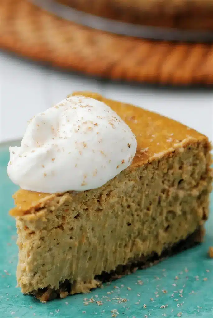 Tall wedge of a creamy spiced dessert with whipped cream on a teal surface