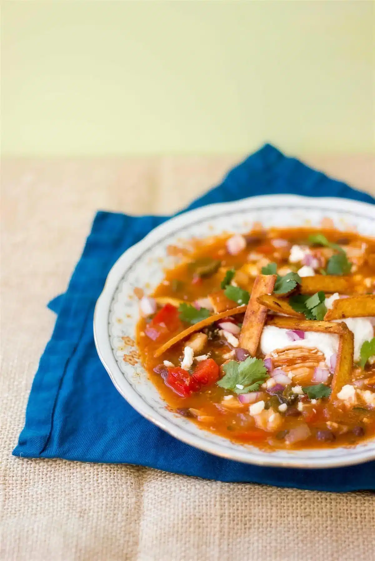 Chicken tortilla soup in a floral bowl set on a folded blue napkin