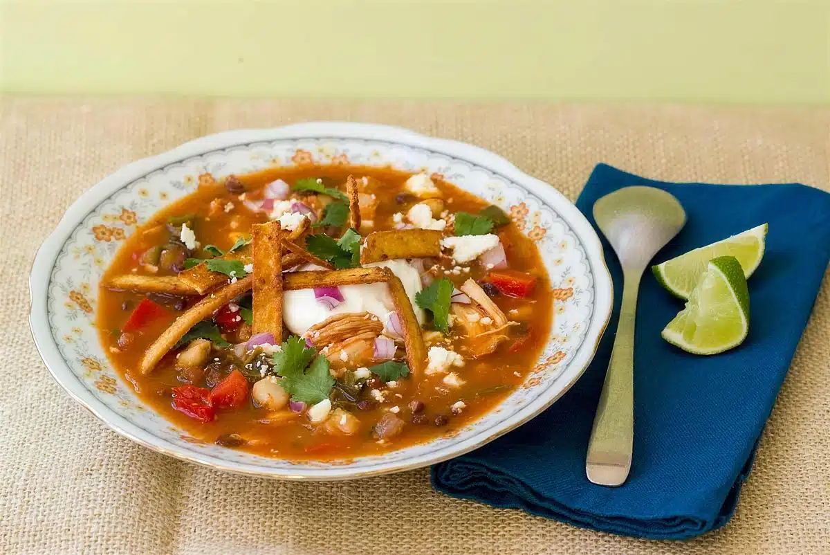 Chicken tortilla soup served in a shallow bowl with crisp strips on top