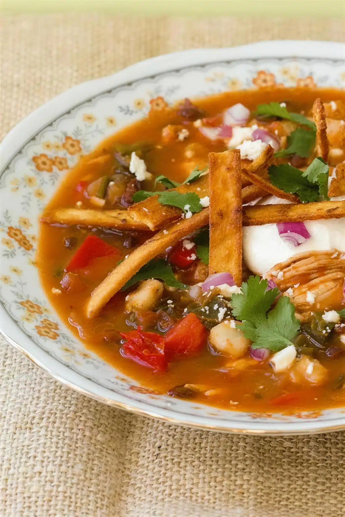 Close up of hominy, black beans and shredded meat in a deep red broth