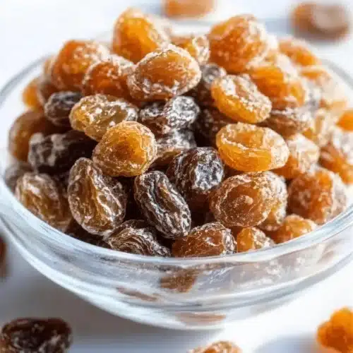 Pale glazed dried fruit in a clear glass bowl with a few beside it