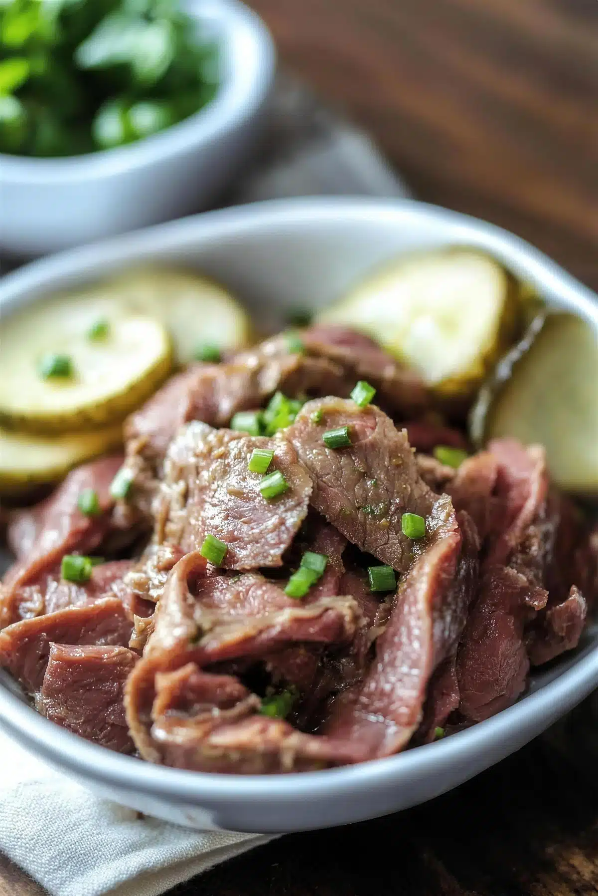 Sliced cured meat in a shallow bowl topped with chopped chives