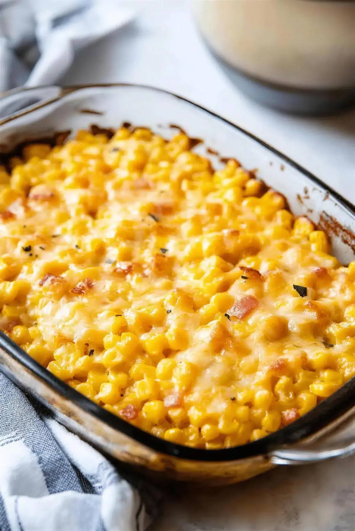 Jack Stack style cheesy corn with diced ham and chopped parsley in a baking dish