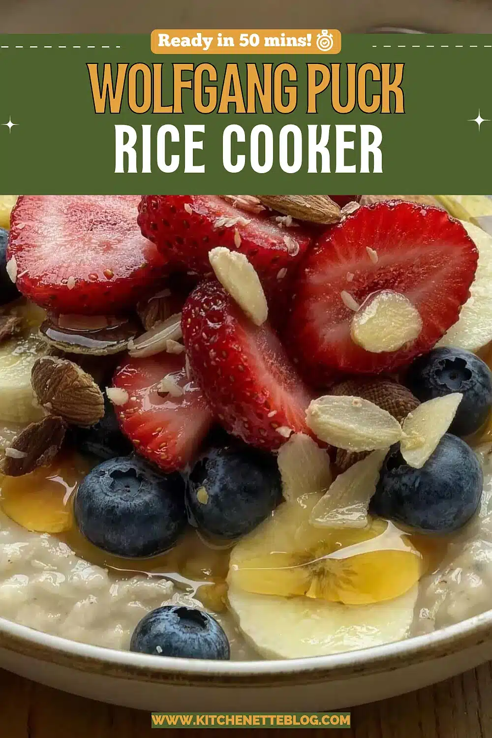 A speckled bowl of creamy porridge topped with halved strawberries, blueberries, banana coins, sliced almonds and a drizzle of honey