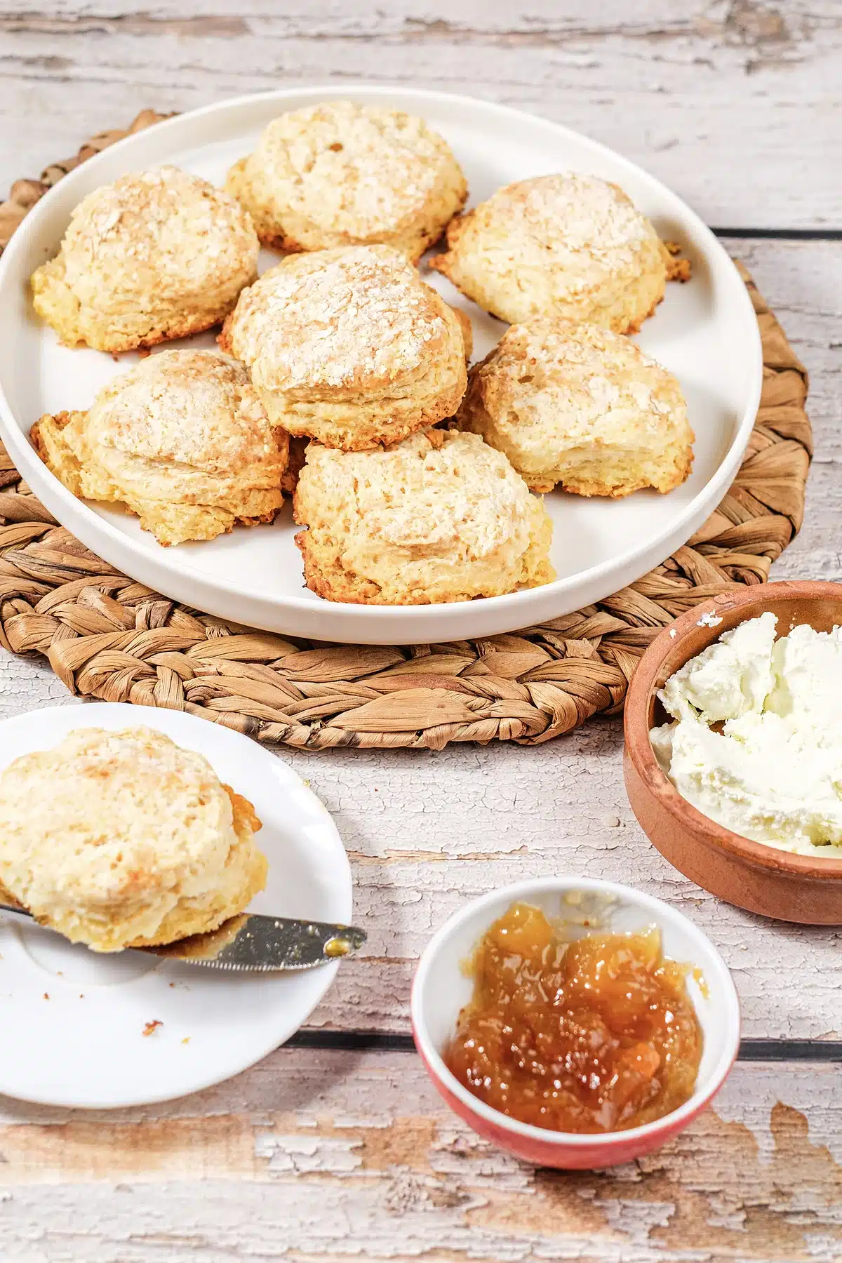 7Up biscuits piled on a white plate with jam and soft cheese below