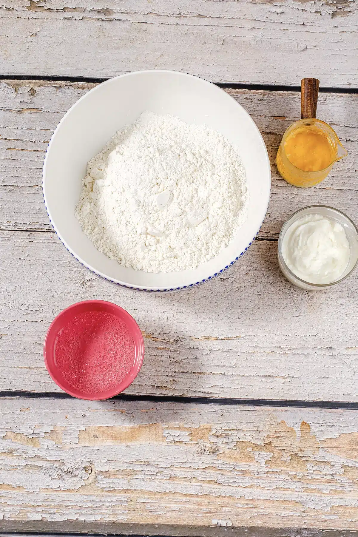 A bowl of baking mix with melted butter, sour cream and a small pink cup alongside