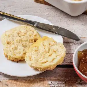 One split 7Up biscuit on a small white plate beside a knife