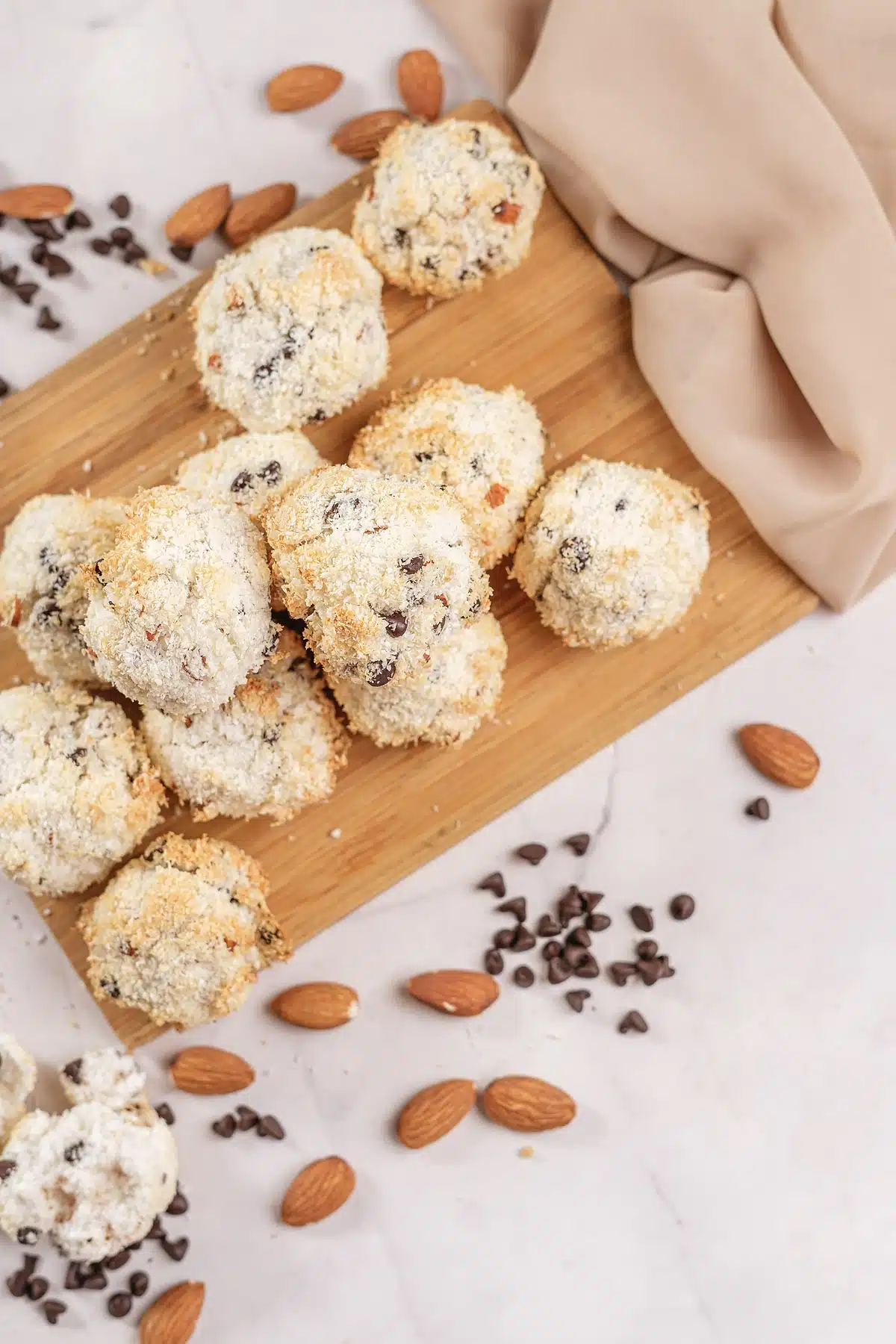 Almond Joy cookies crowded onto a board with a beige linen napkin behind