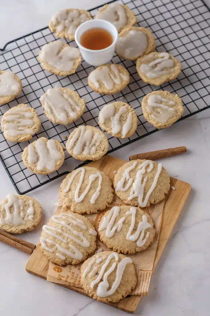 Apple cider cookies with cider glaze on a wire rack and a wooden board, seen from directly above