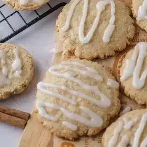 A single apple cider cookie with a piped zigzag of cider glaze on a wooden board