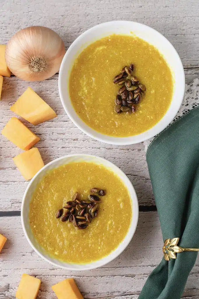 Panera autumn squash soup served in two white bowls on a pale wooden table