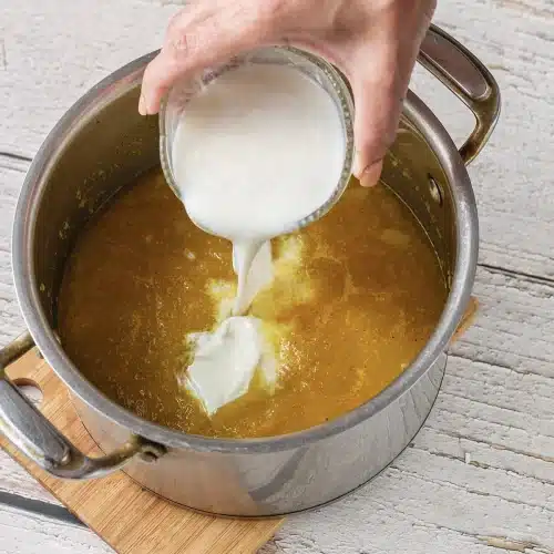 Cream poured into the pot of blended soup