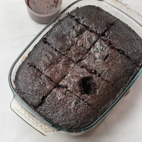 The poked cake with the bowl of chocolate filling ready beside the dish