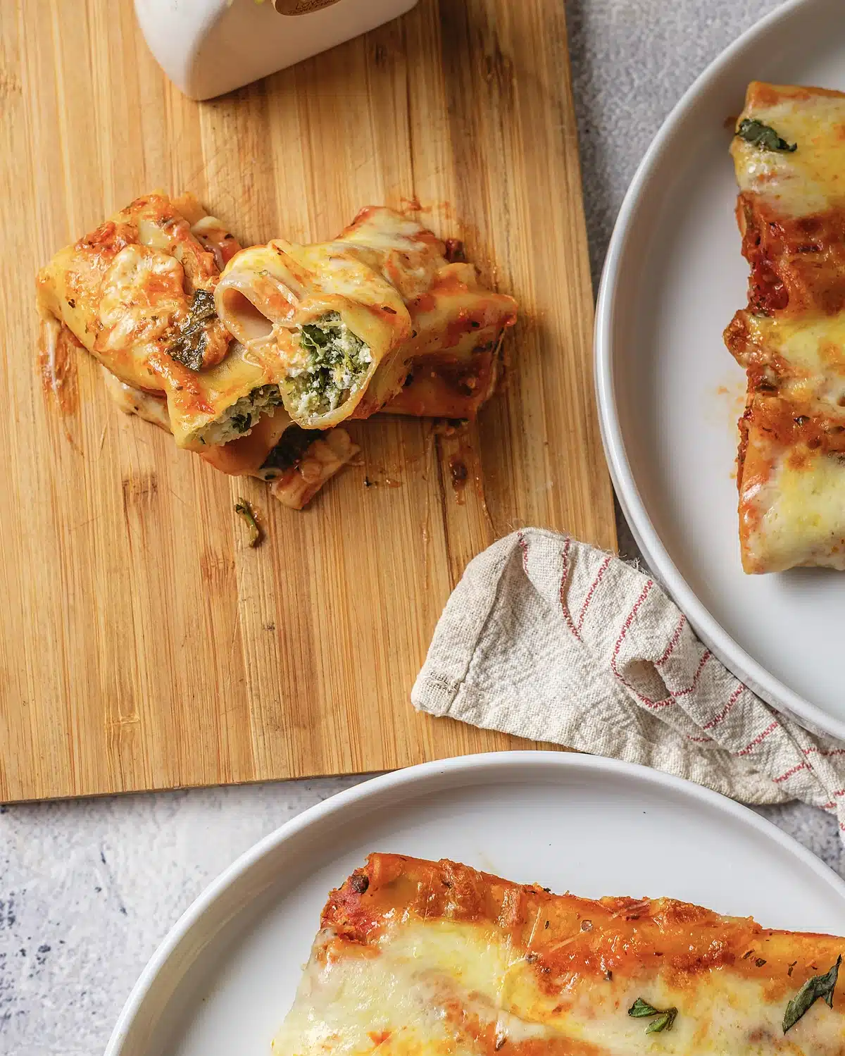 A board of pasta tubes cut open to show the green ricotta filling