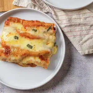 A single serving of baked manicotti on a small white plate