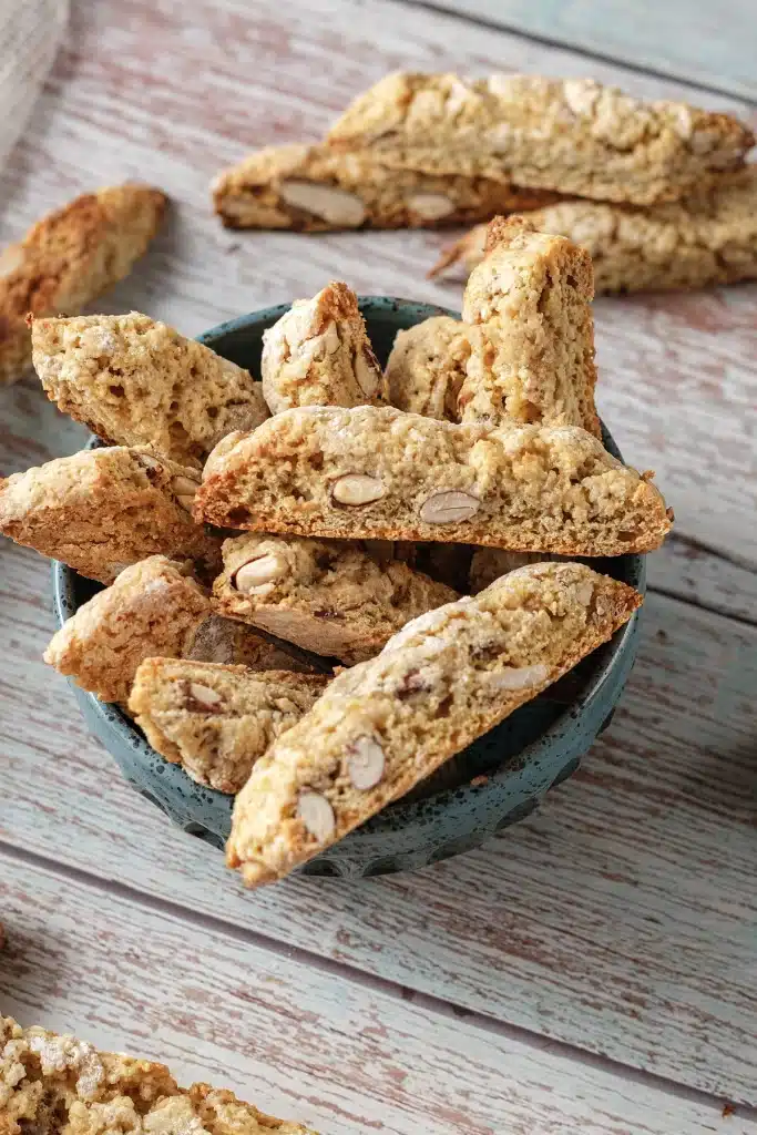 Almond biscotti standing upright in a speckled blue bowl seen from above