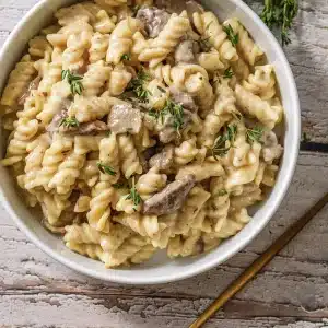 One bowl of beef stroganoff topped with fresh thyme leaves