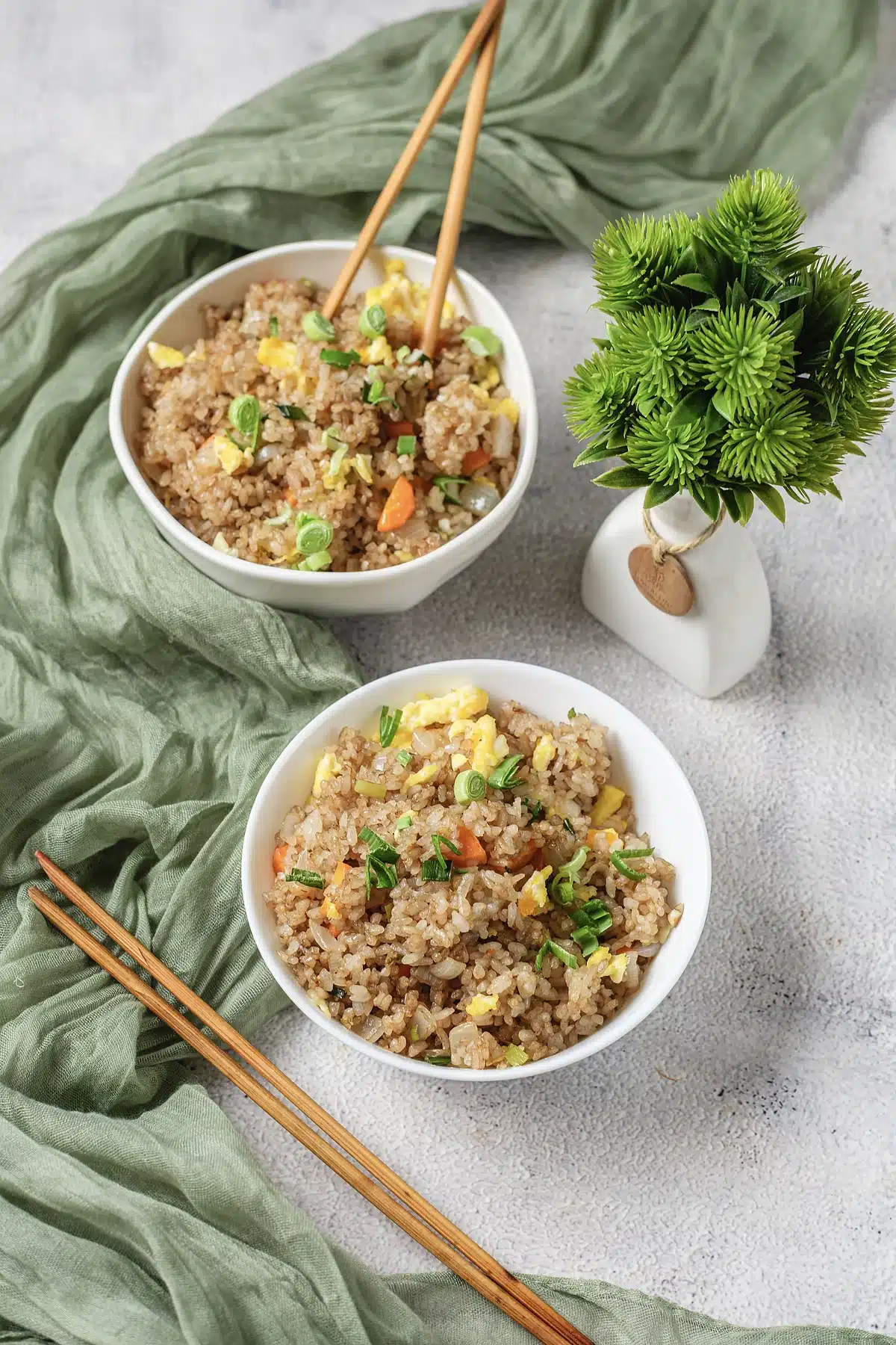 Benihana fried rice in two white bowls with chopsticks and a green cloth