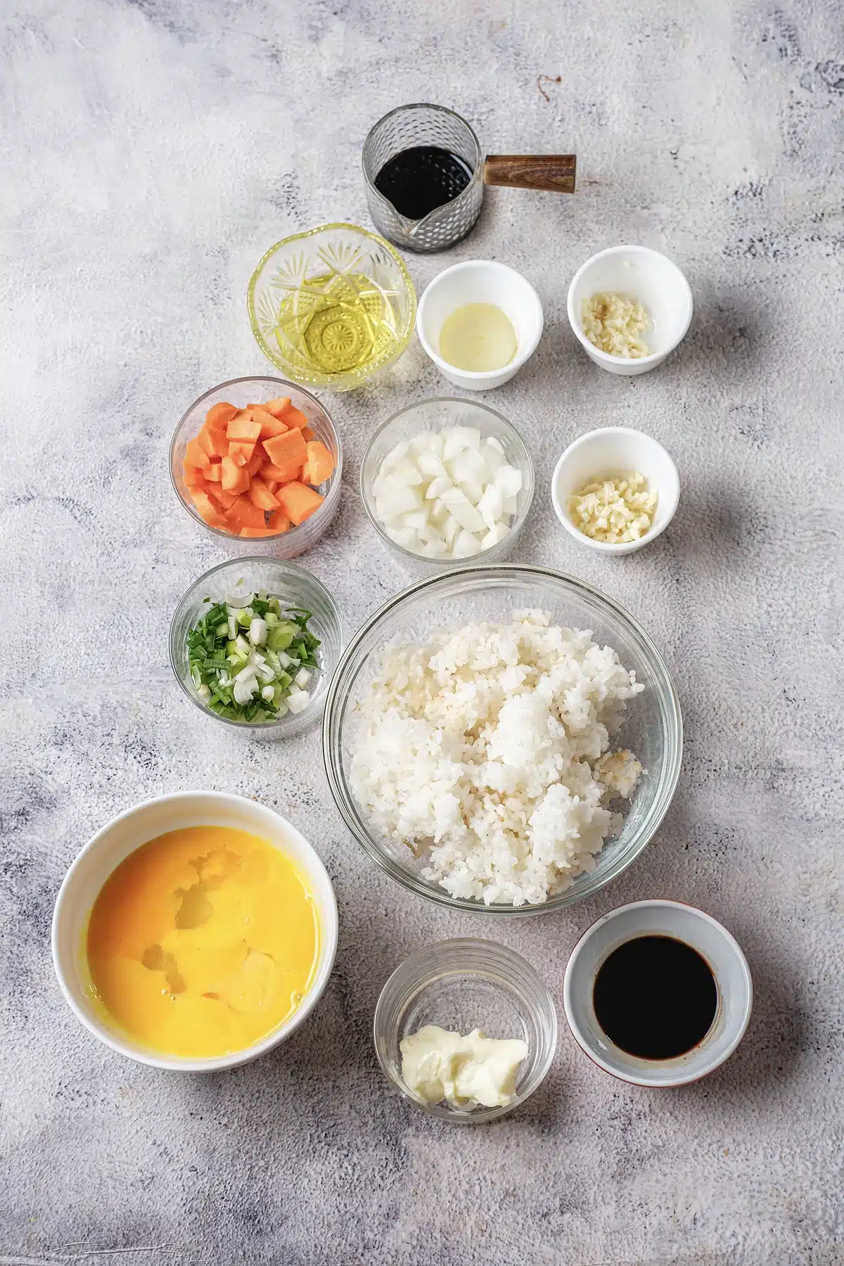 Diced carrot, onion, scallion, garlic, butter, egg and soy sauce in glass bowls