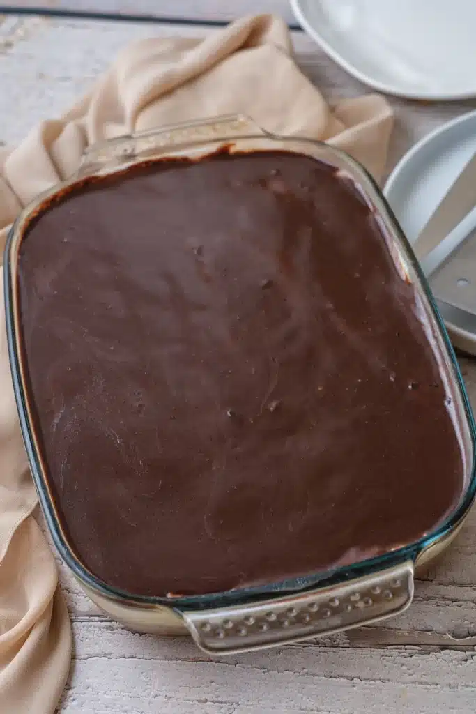 Boston cream poke cake whole in its glass dish with a set chocolate top, seen from directly above