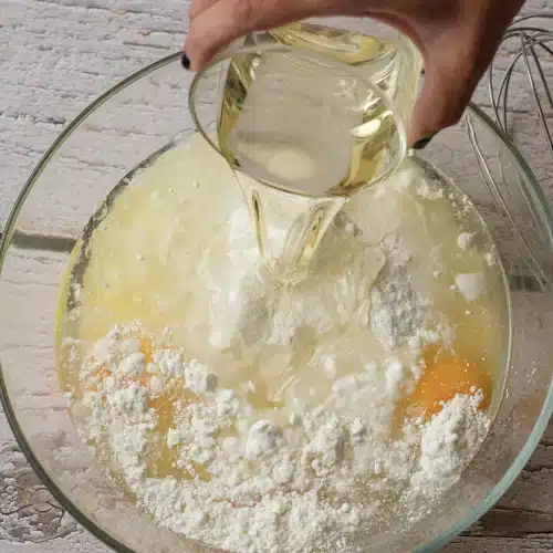 Oil poured into the bowl of mix, eggs and water