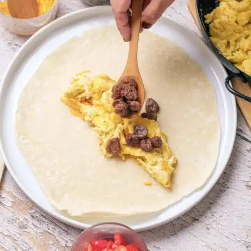 Scrambled eggs and sausage crumbles spooned onto the center of a flour tortilla