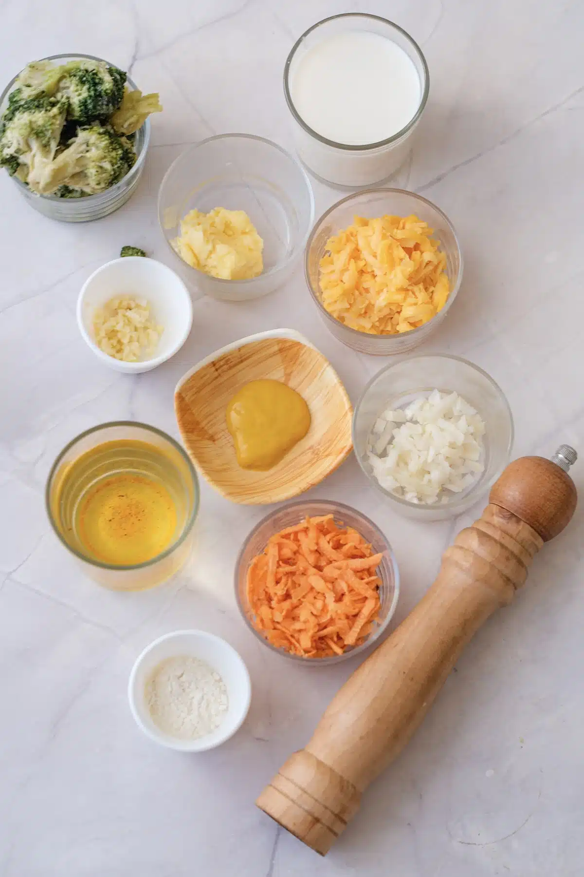 Broccoli florets, butter, milk, shredded cheddar, garlic, Dijon mustard, onion, broth, shredded carrot and flour laid out in bowls