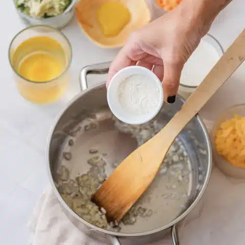 Flour tipped from a small bowl over the softened onion